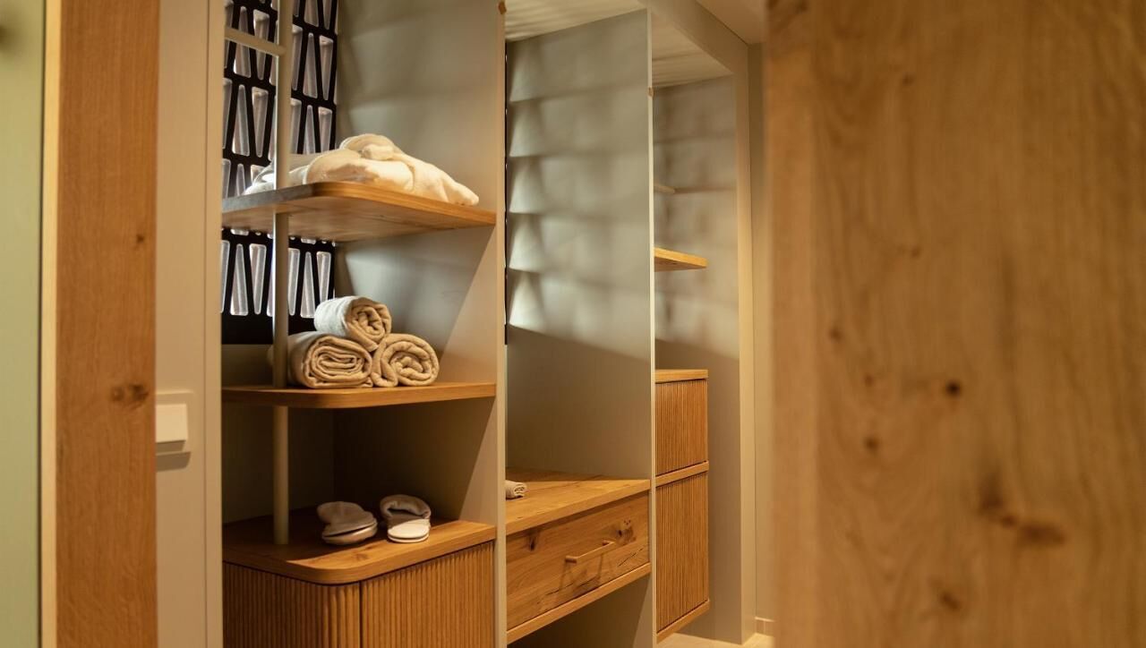 Ein Holzschrank mit Regalen, einem Schuhregal und einer Kleiderstange für Handtücher.