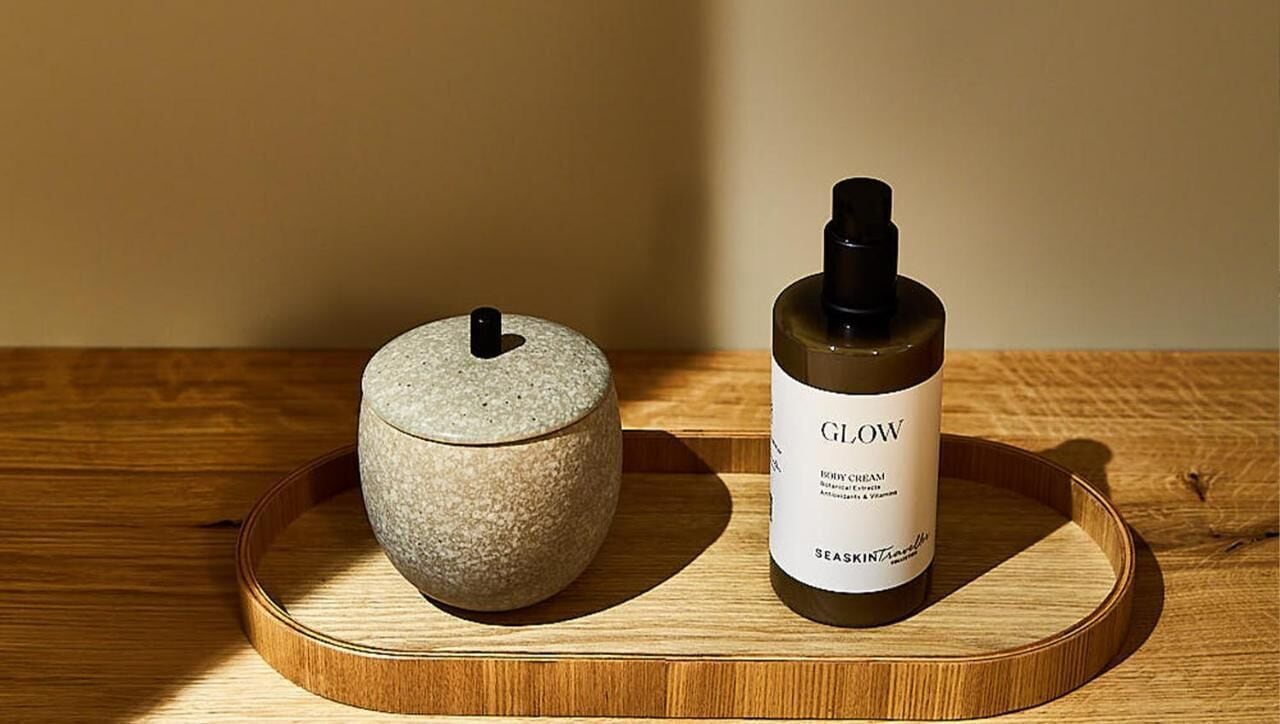 A wooden tray with a stone container and a bottle of Glow skincare product.