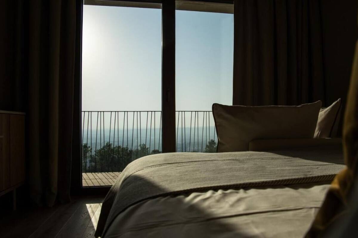 Ein Schlafzimmer mit einem großen Bett, Meerblick und einem Balkon mit Geländer.