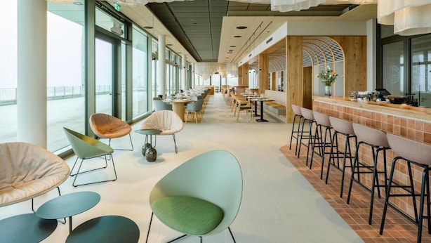 A modern interior with a long bar area, seating with unique chairs, and large windows providing natural light. - Wald.Weit Rheingau Hotel und Retreat (Kiedrich)