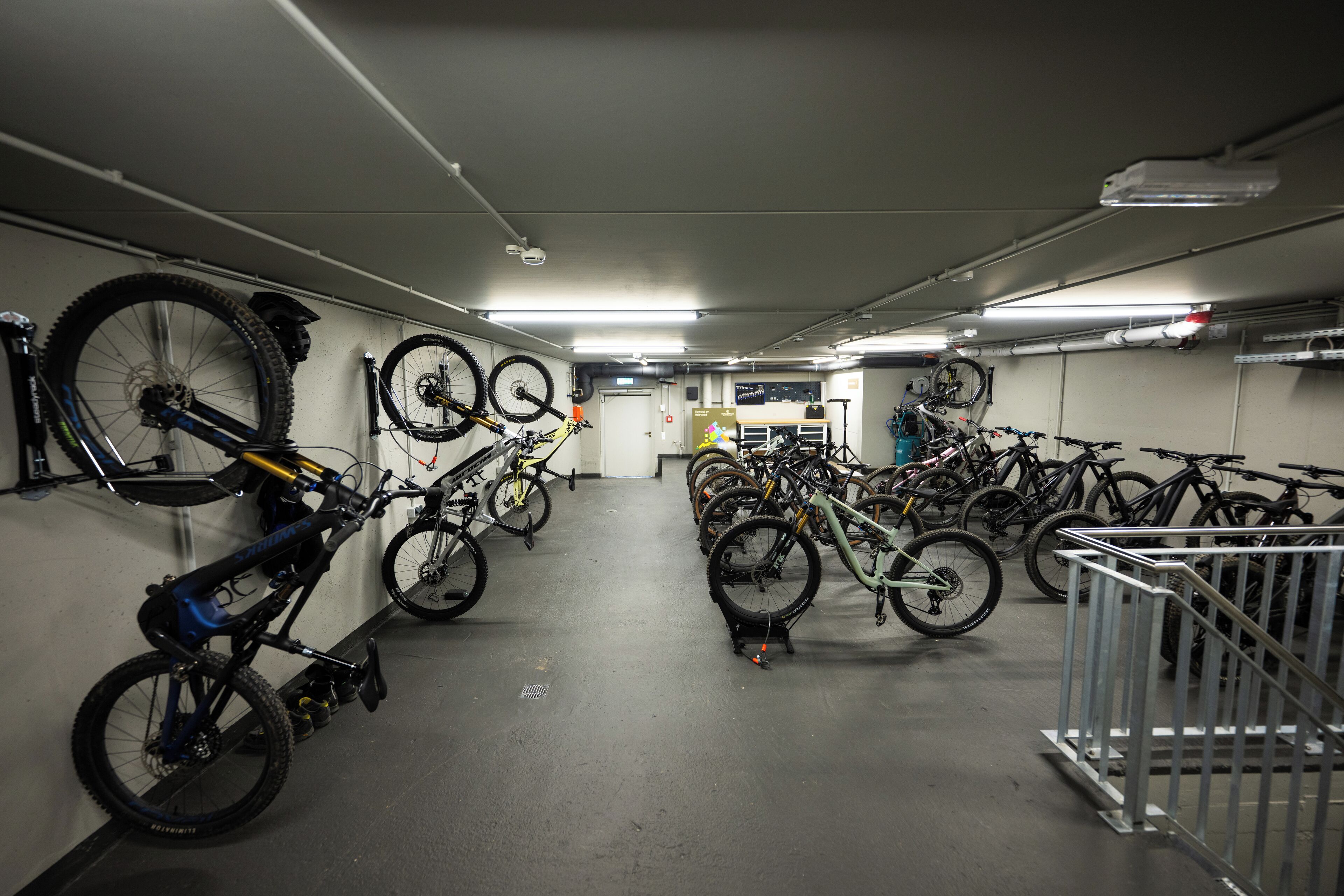 A bike storage area with multiple bicycles parked against the walls and on racks.