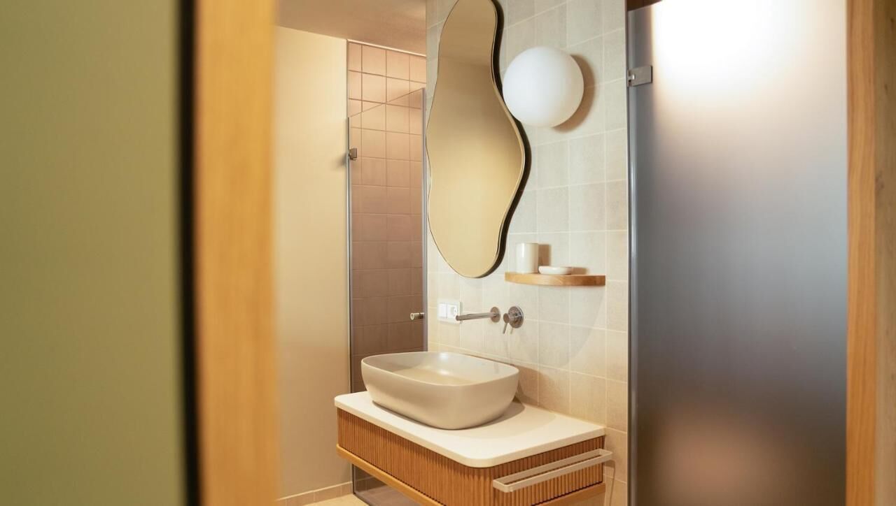 Un baño con un espejo grande, un lavabo sobre encimera y un mueble de tocador de madera.
