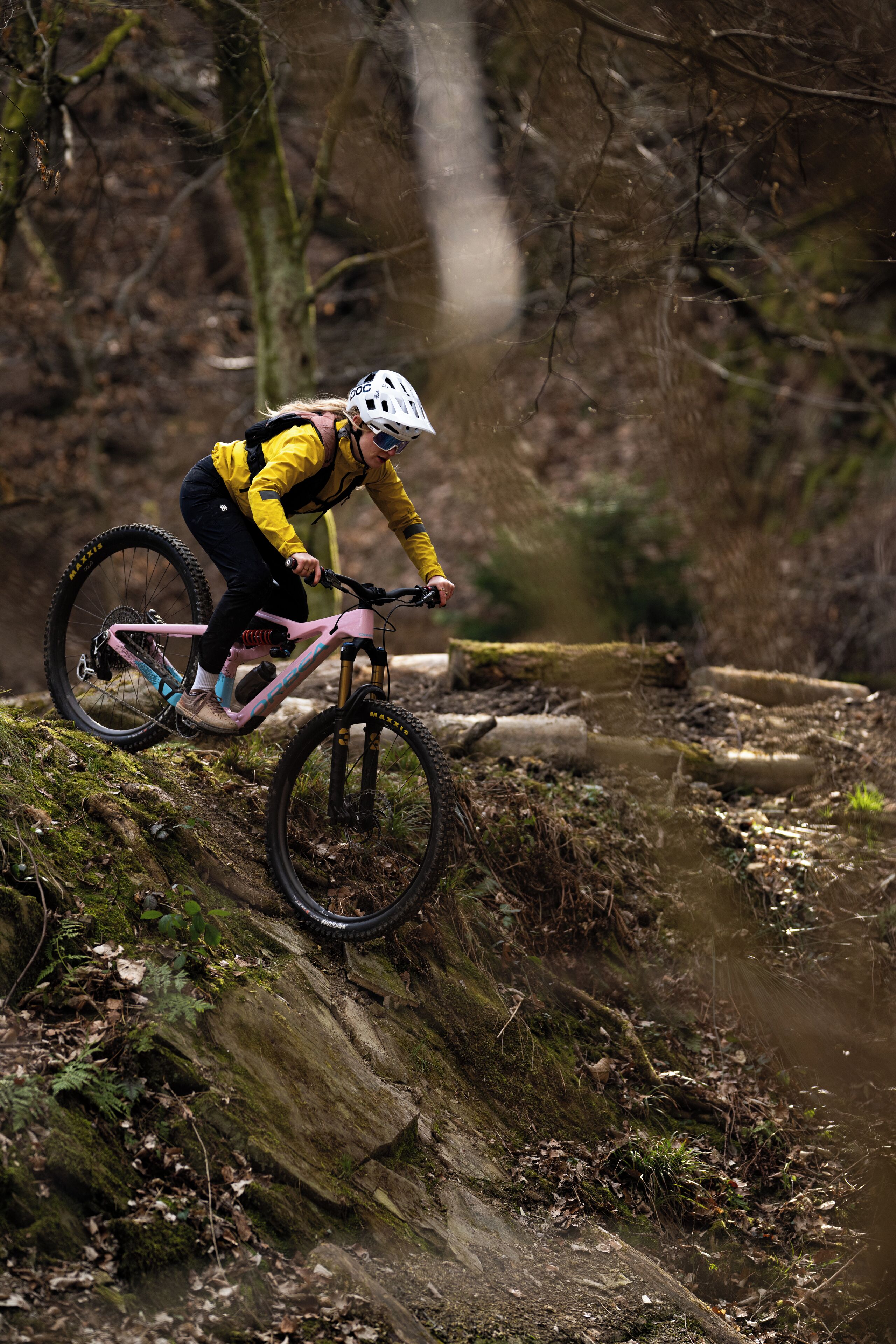 A mountain biker on a trail with natural terrain and trees.