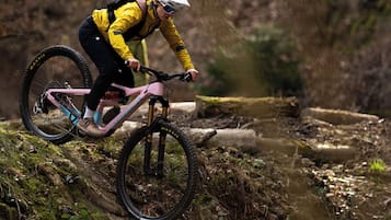 A mountain biker on a trail with natural terrain and trees.