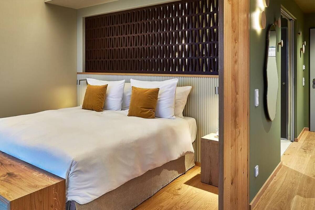 Ein modernes Schlafzimmer mit einem großen Bett, einem Holz-Kopfteil und einem kleinen Nachttisch.