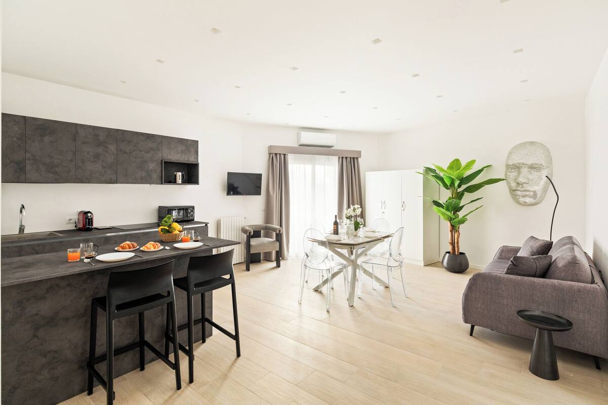 A modern kitchen with a bar area, dining table, and seating.
