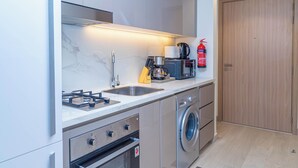 A modern kitchen with a gas stove, sink, and built-in washing machine. - Bloomfields Fantastic STU Azizi Riviera (Dubai)