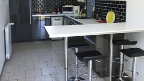 Una cocina moderna con una isla central, electrodomésticos de acero inoxidable y taburetes negros.