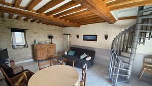 Un espacio acogedor con una mesa de comedor, sillas de madera, un sofá y una escalera.