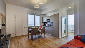Un apartament modern amb zona de menjador, cuina i un sofà vermell.