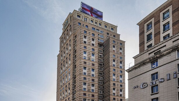 Un edifici alt i rectangular amb una bandera destacada a la part superior i un cartell que diu "Gasli".