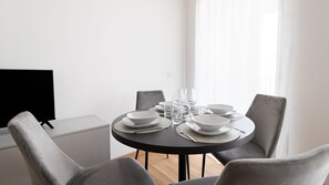 A modern dining area with a round table set for four, equipped with plates, bowls, glasses, and cutlery.