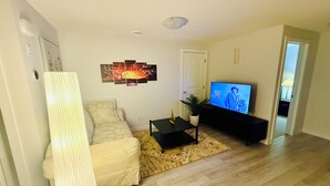 Ein Wohnzimmer mit einer Couch, einem Couchtisch, einem Fernseher und einem Bild an der Wand.