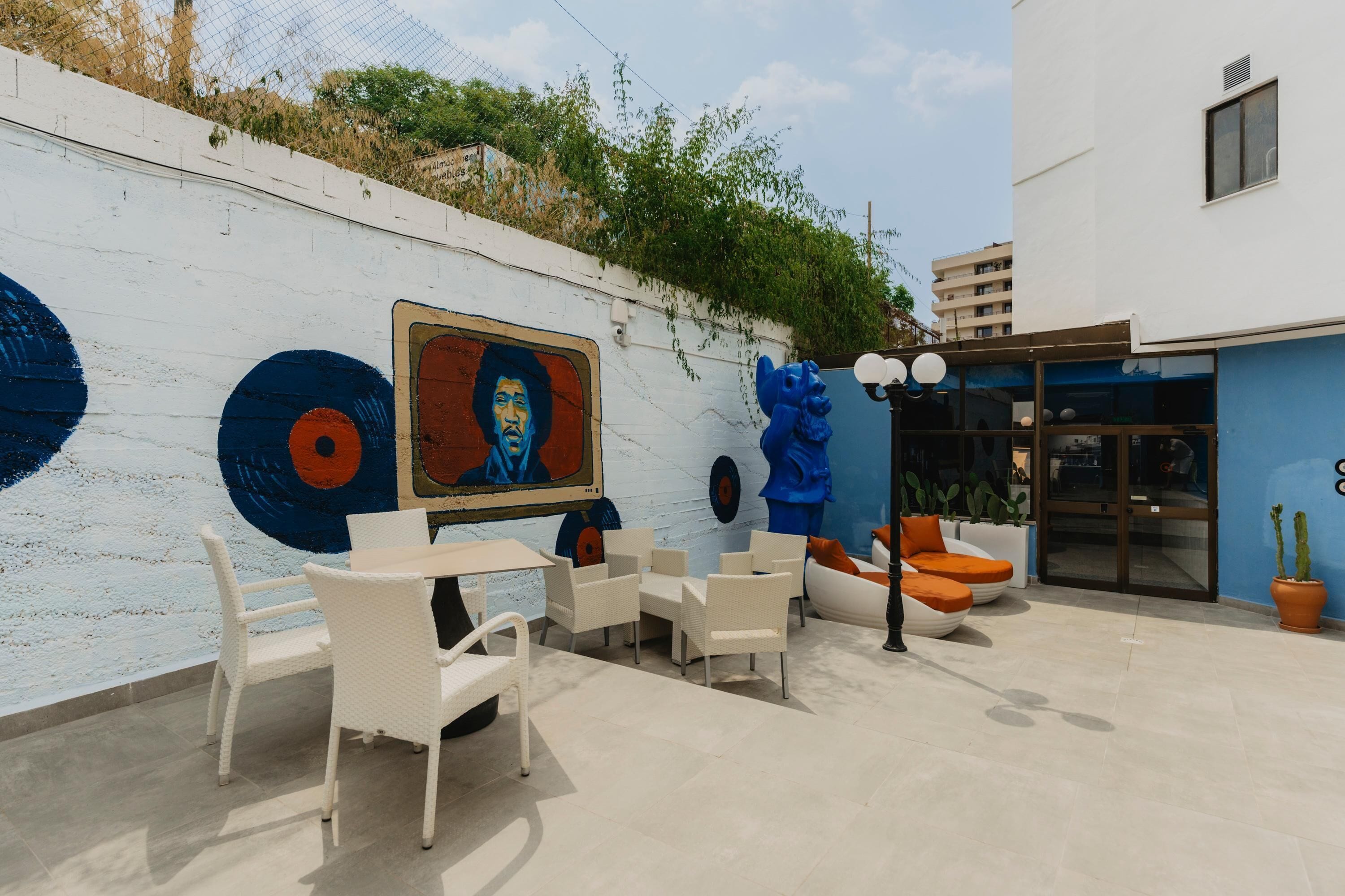 An outdoor seating area with white wicker furniture and a mural on the wall.