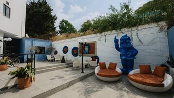 An outdoor seating area with modern furniture, a mural, and a statue.