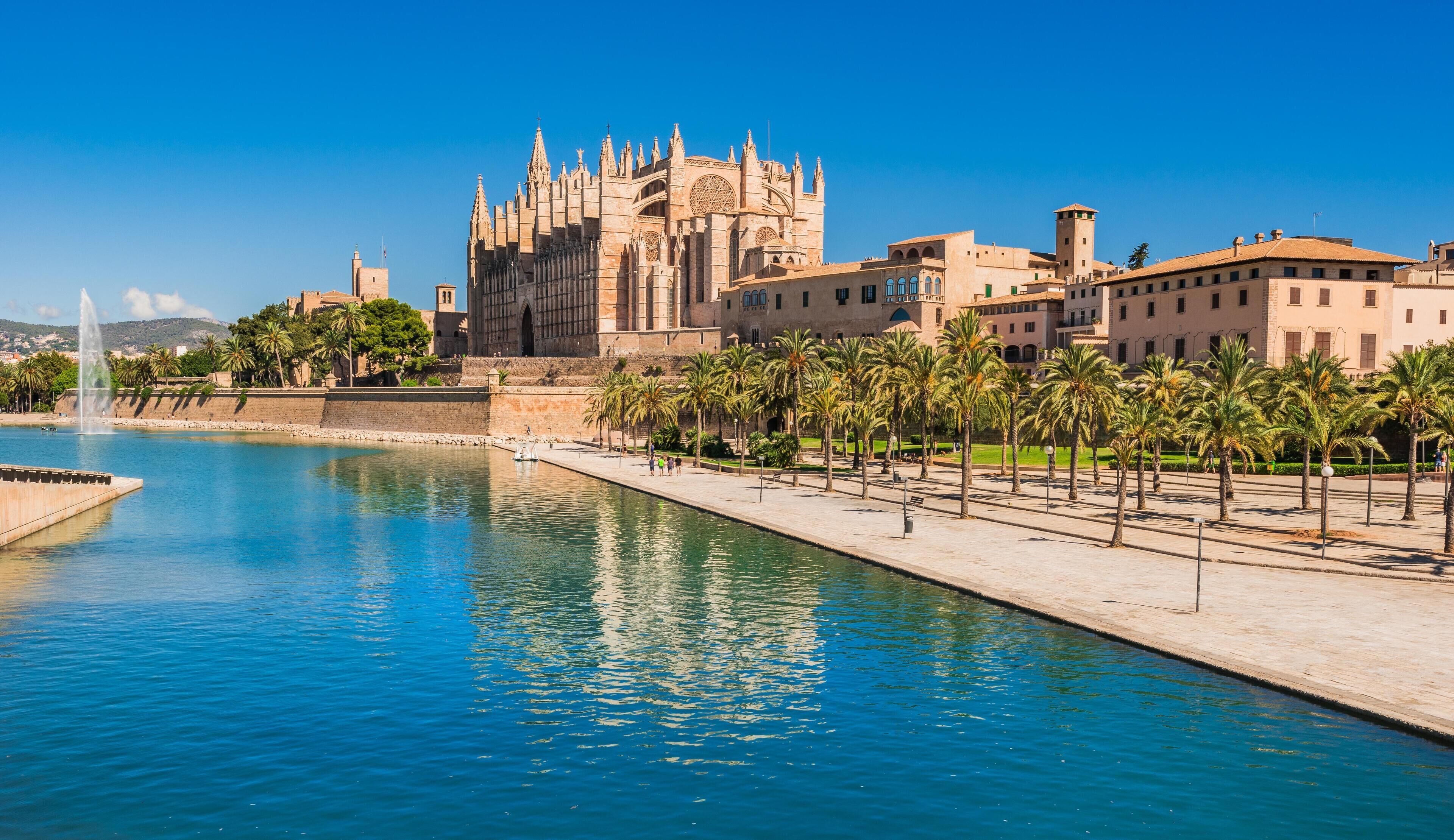 A historic building with a large courtyard, palm trees, and a fountain.