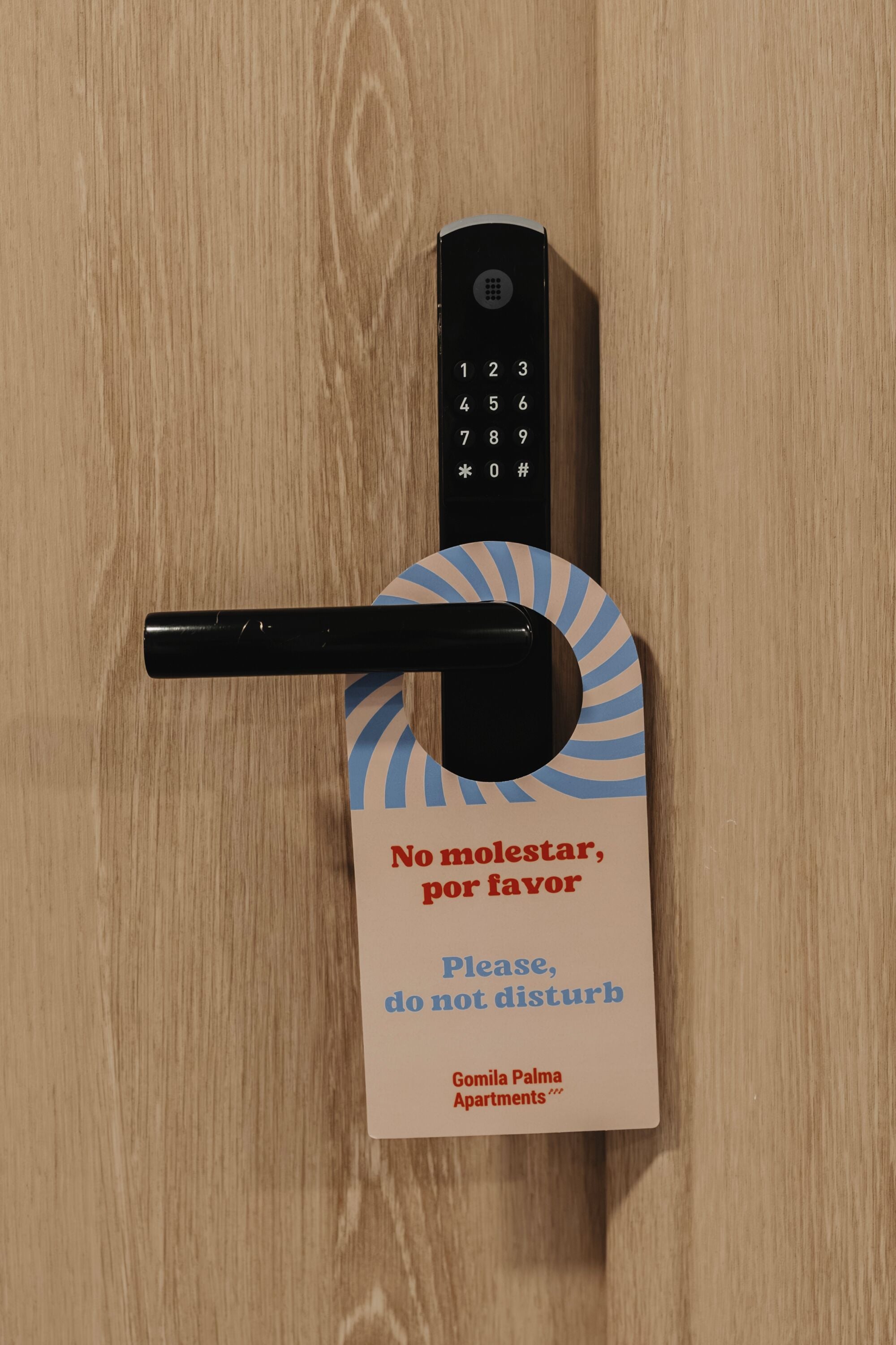 A door lock with a keyhole and a sign that reads 'No molestar, por favor do not disturb' for Gomila Palma Apartments.
