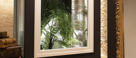 A room with a large window, wooden floor, and a wall-mounted mirror.