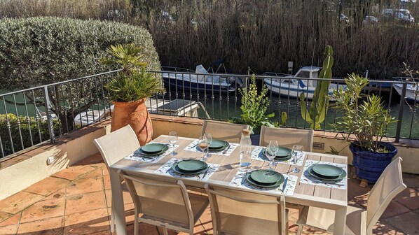 A table set for four with green plates and wine glasses, overlooking a marina with boats.