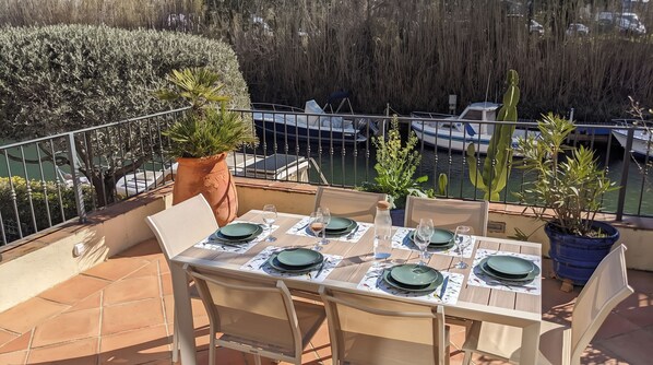 An outdoor dining area with a table set for four, overlooking a marina with boats. - By the water: XXL terrace, paddle, bicycles, and air conditioning. New in 2025 + 2 secure garages (Cogolin)