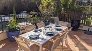 An outdoor dining area with a table set for four, surrounded by chairs, potted plants, and a railing. - By the water: XXL terrace, paddle, bicycles, and air conditioning. New in 2025 + 2 secure garages (Cogolin)