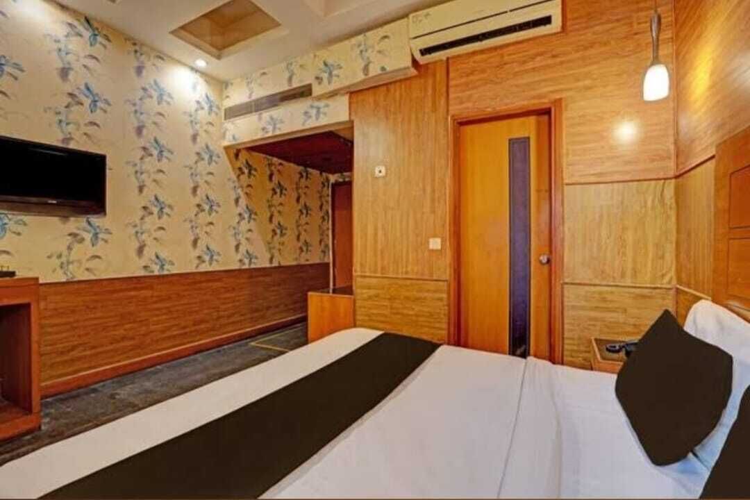 Una habitación de hotel con cama, televisión, armario de madera y diseño de papel tapiz floral.