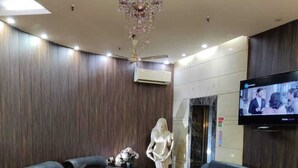 A modern lounge with leather sofas, a glass coffee table, and a chandelier. - HOTEL O ONE HOTEL (Ghaziabad)