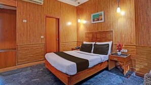 A wooden-paneled room with a bed, a nightstand, and a wall-mounted lamp. - HOTEL O ONE HOTEL (Ghaziabad)