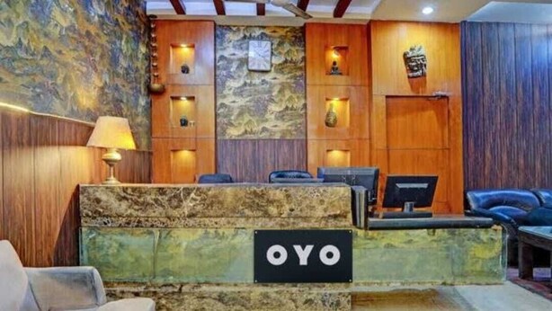 A reception desk with a sign reading "OYO" in a lobby with wooden paneling and a stone accent wall. - HOTEL O ONE HOTEL (Ghaziabad)