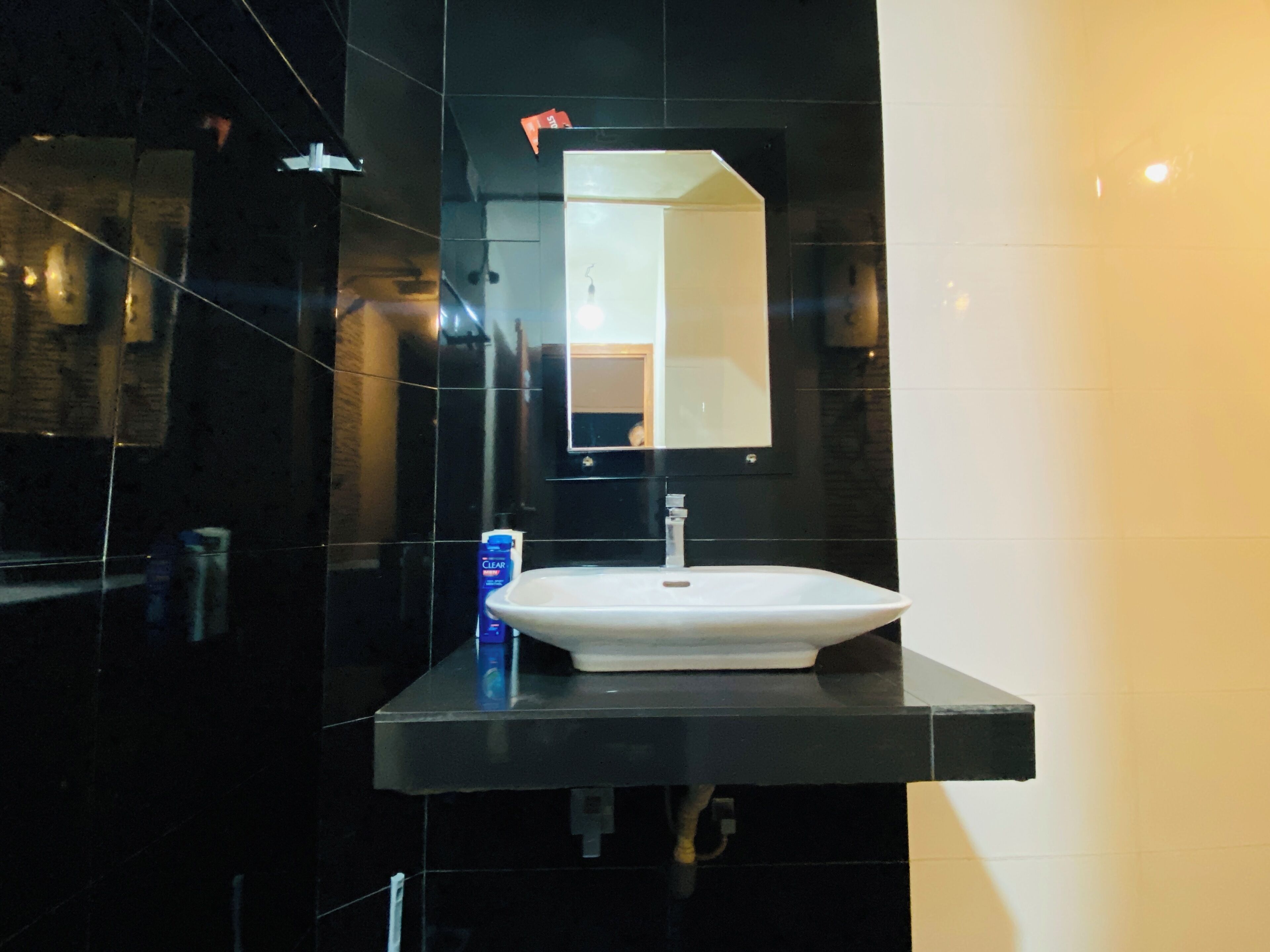 Ein modernes Badezimmer mit einem weißen Waschbecken, einer schwarzen Arbeitsplatte und einem Spiegel darüber.