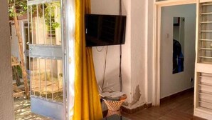 A living room with a TV mounted on the wall, a sofa, a small coffee table, and a patterned rug. - Kogelo Retreat Villas and Homes Kisumu (Kisumu)