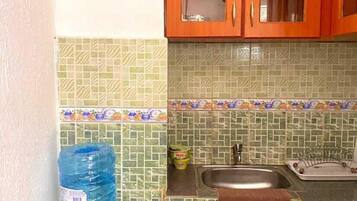 Una pequeña cocina con dispensador de agua, un lavamanos y una estufa a gas.