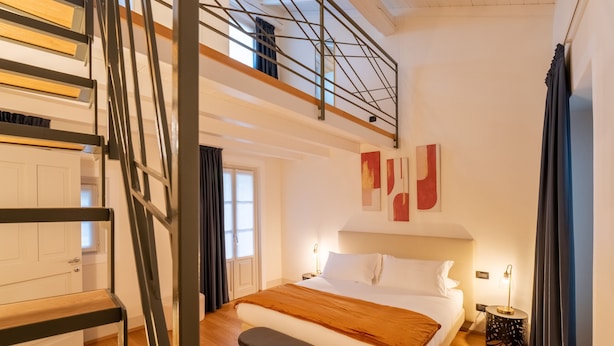 A bedroom with a bed, bench, and a staircase leading to an upper level. - Palazzo Odescalchi by Wonderful Italy - Apt 7 (Como)