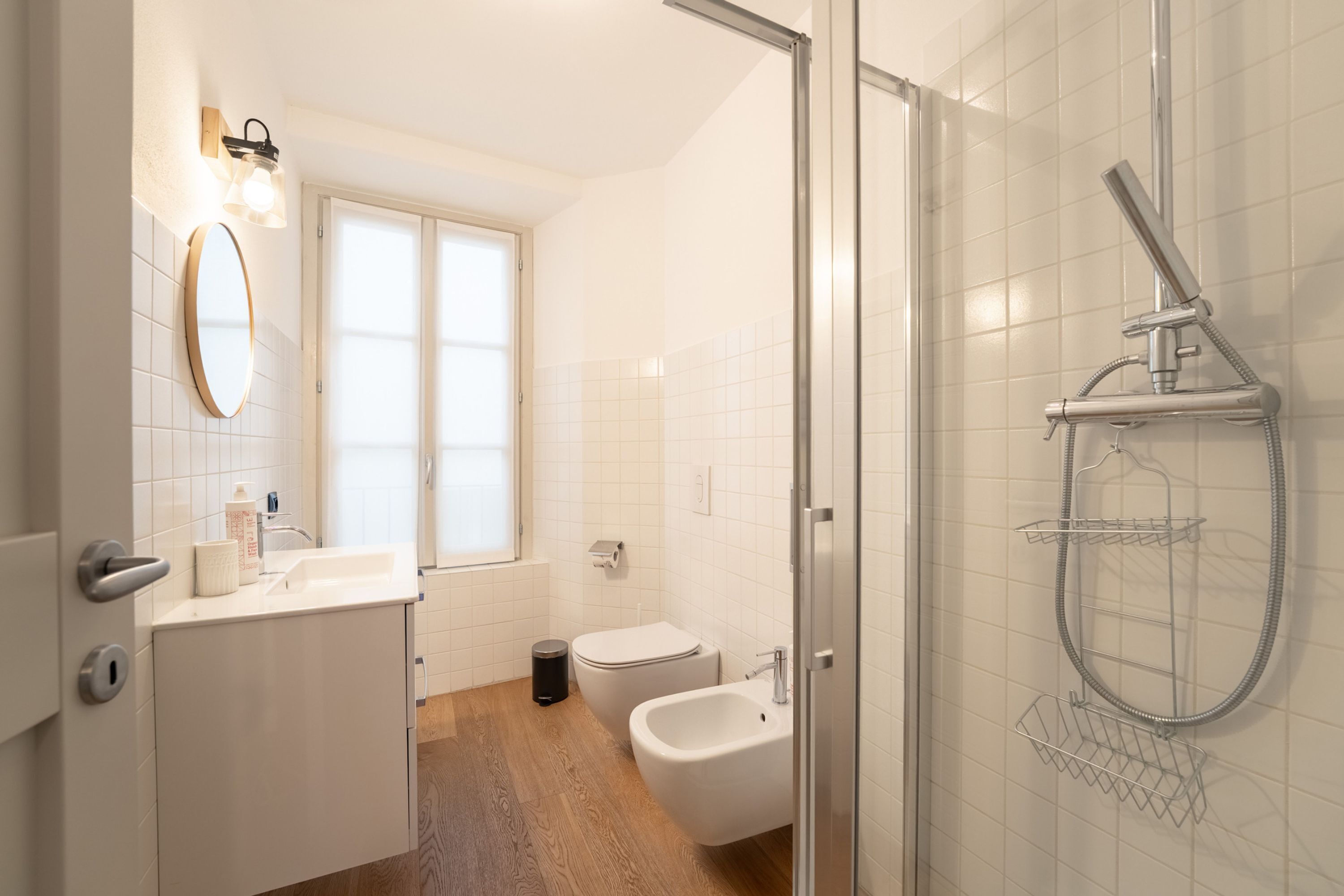 A modern bathroom with a glass shower enclosure, a white sink, and a bidet.