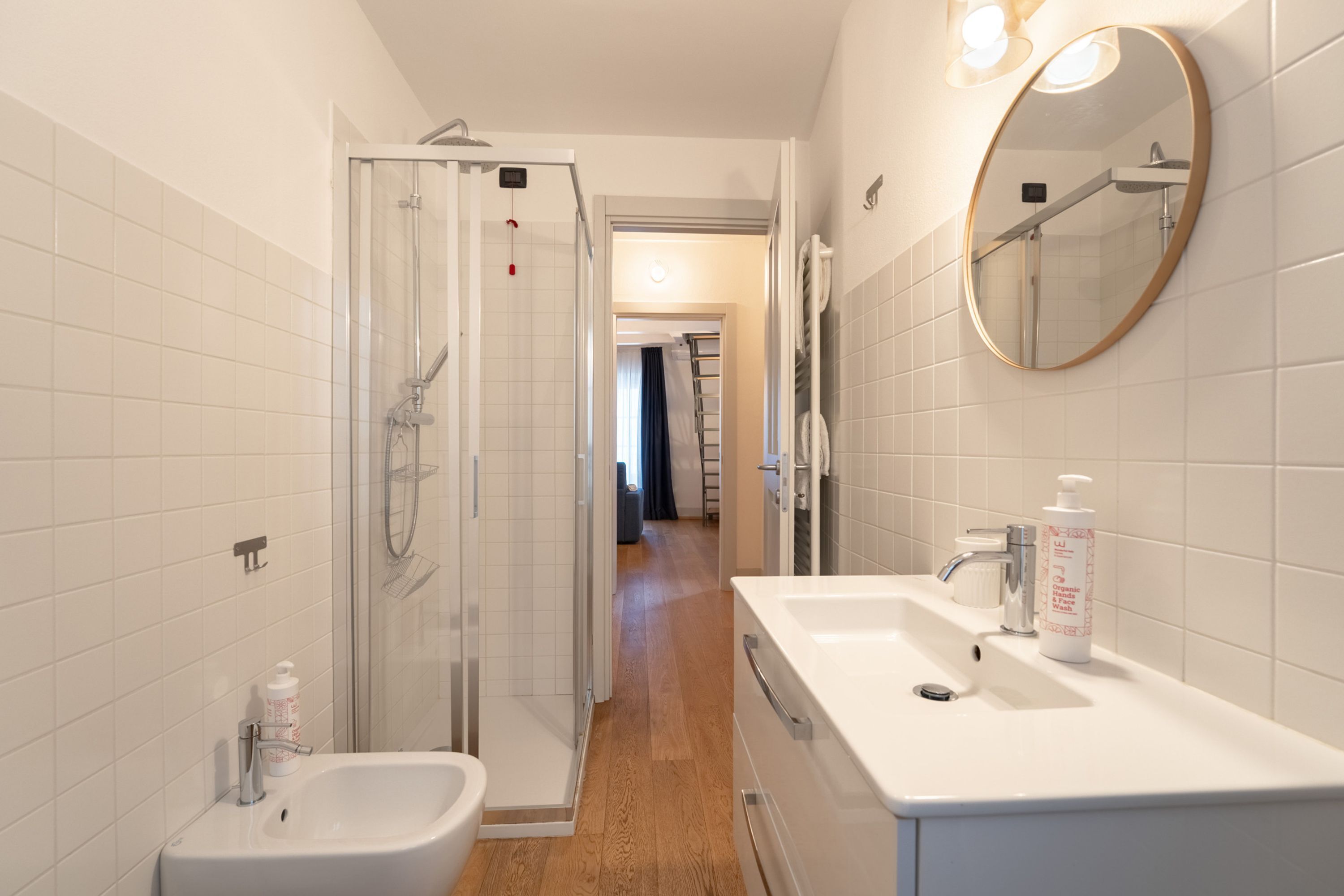 A modern bathroom with a glass shower enclosure, a white sink, and a mirror.