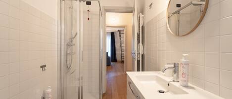 A modern bathroom with a glass shower enclosure, a white sink, and a mirror.