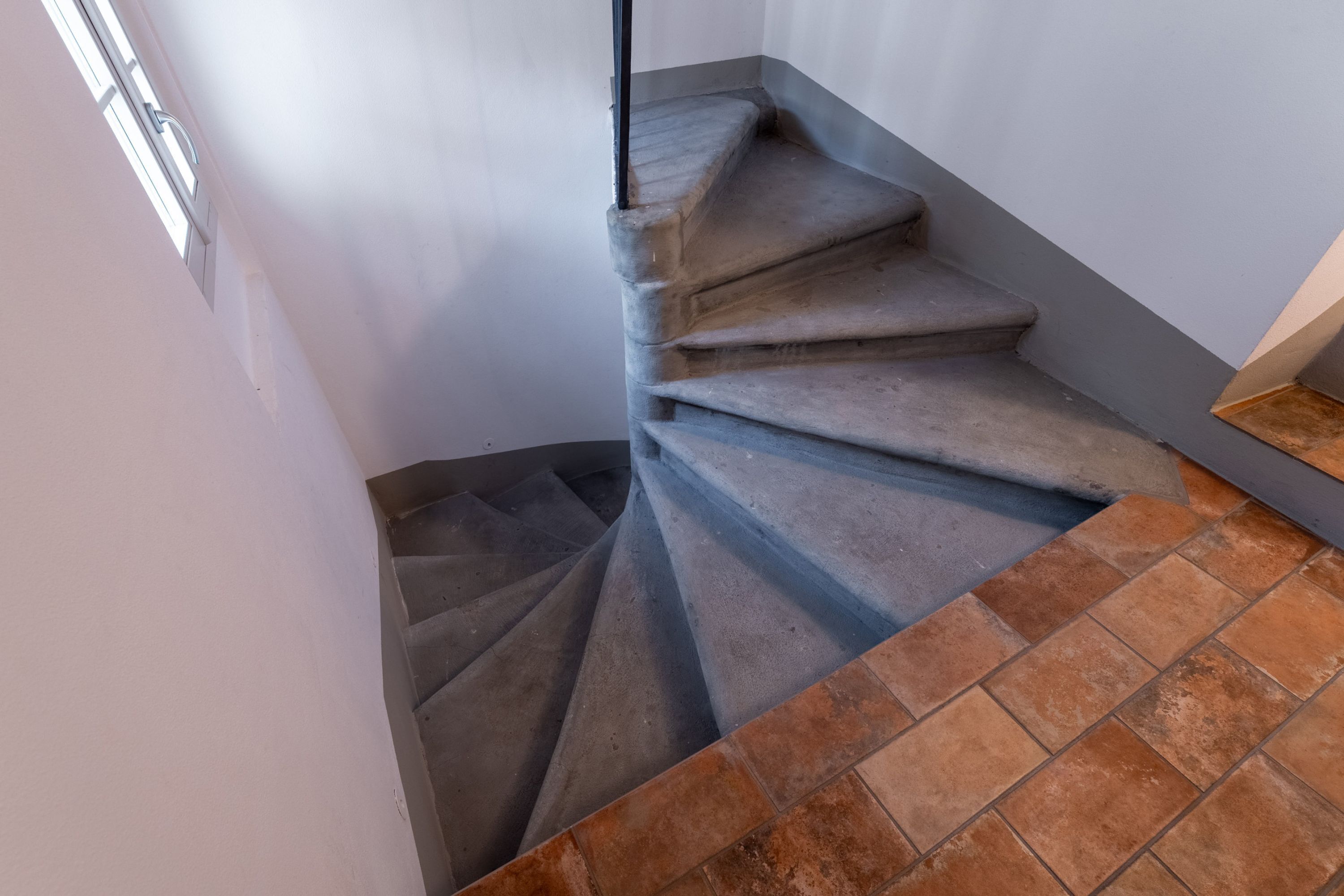 Una escalera de caracol con barandilla y un rellano con azulejos.