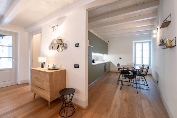 Une cuisine moderne avec des meubles en bois, un coin repas comprenant une table et des chaises, et une petite table ronde avec une lampe.
