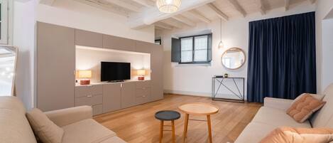 Una sala de estar moderna con un sofá, un televisor, una mesita y un techo con vigas a la vista.