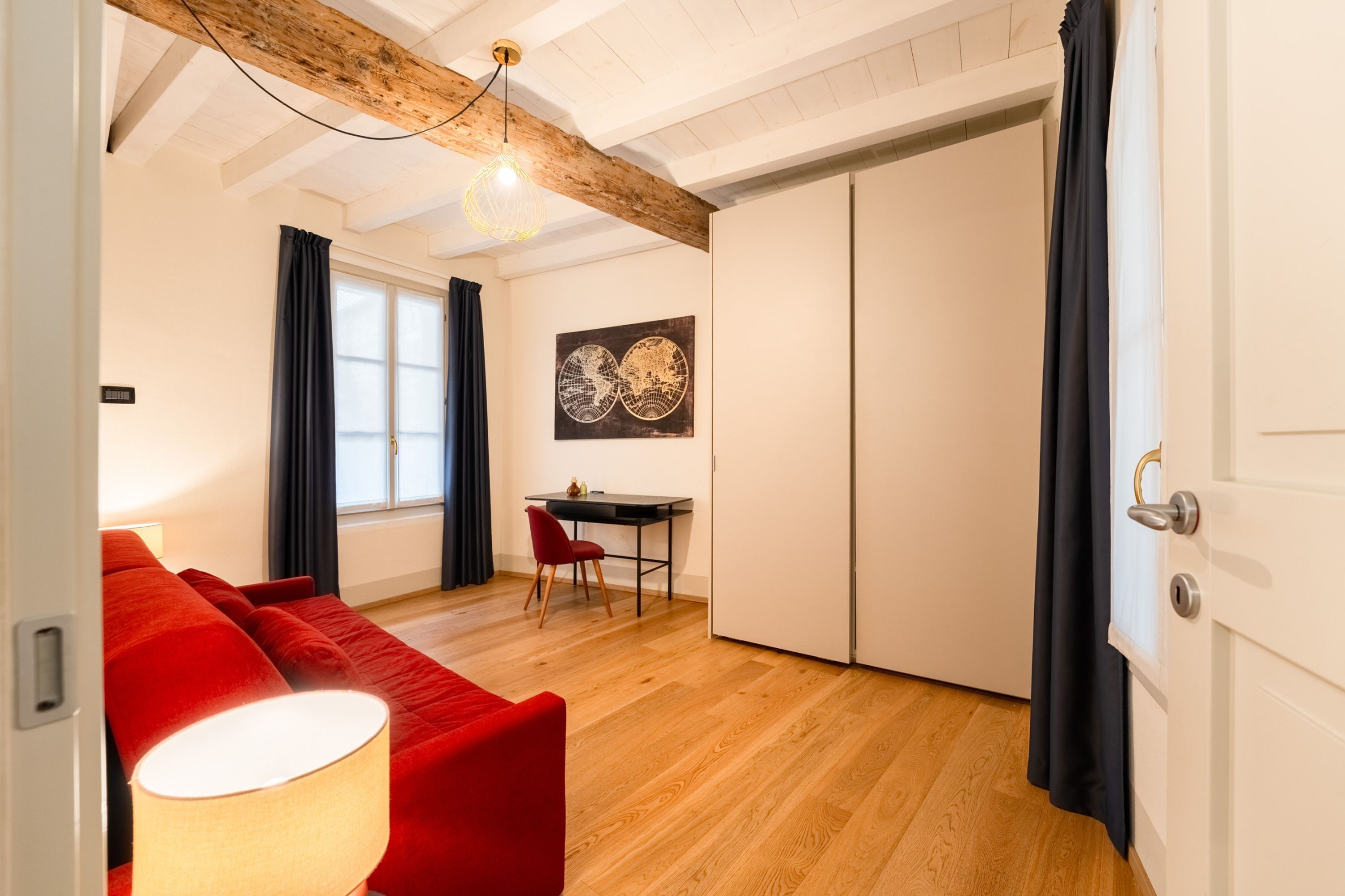 Un salon moderne avec un canapé rouge, une table à manger avec une chaise et un plafond en bois.