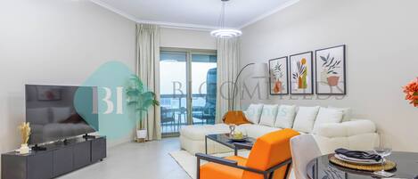 A modern living room with a sofa, a dining table, and a TV. There are potted plants and artwork on the walls.