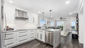 Una cocina moderna con armarios blancos, lavavajillas de acero inoxidable y una isla grande con fregadero.