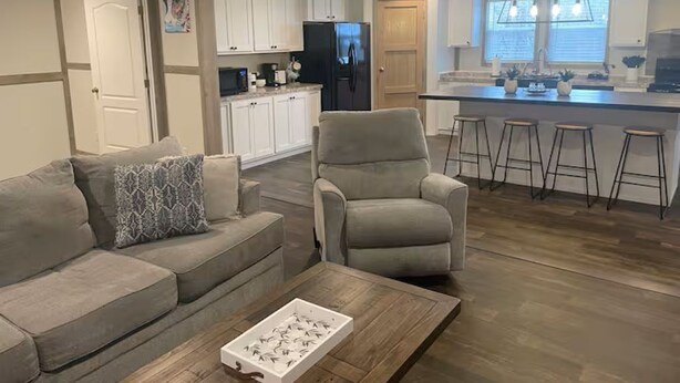 A modern kitchen with white cabinets, a black refrigerator, and a bar area with stools. - Mountain Top Retreat with ATV Route Access (LaFollette)