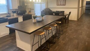 A modern kitchen with a central island, bar stools, and a dining area with chairs. - Mountain Top Retreat with ATV Route Access (LaFollette)