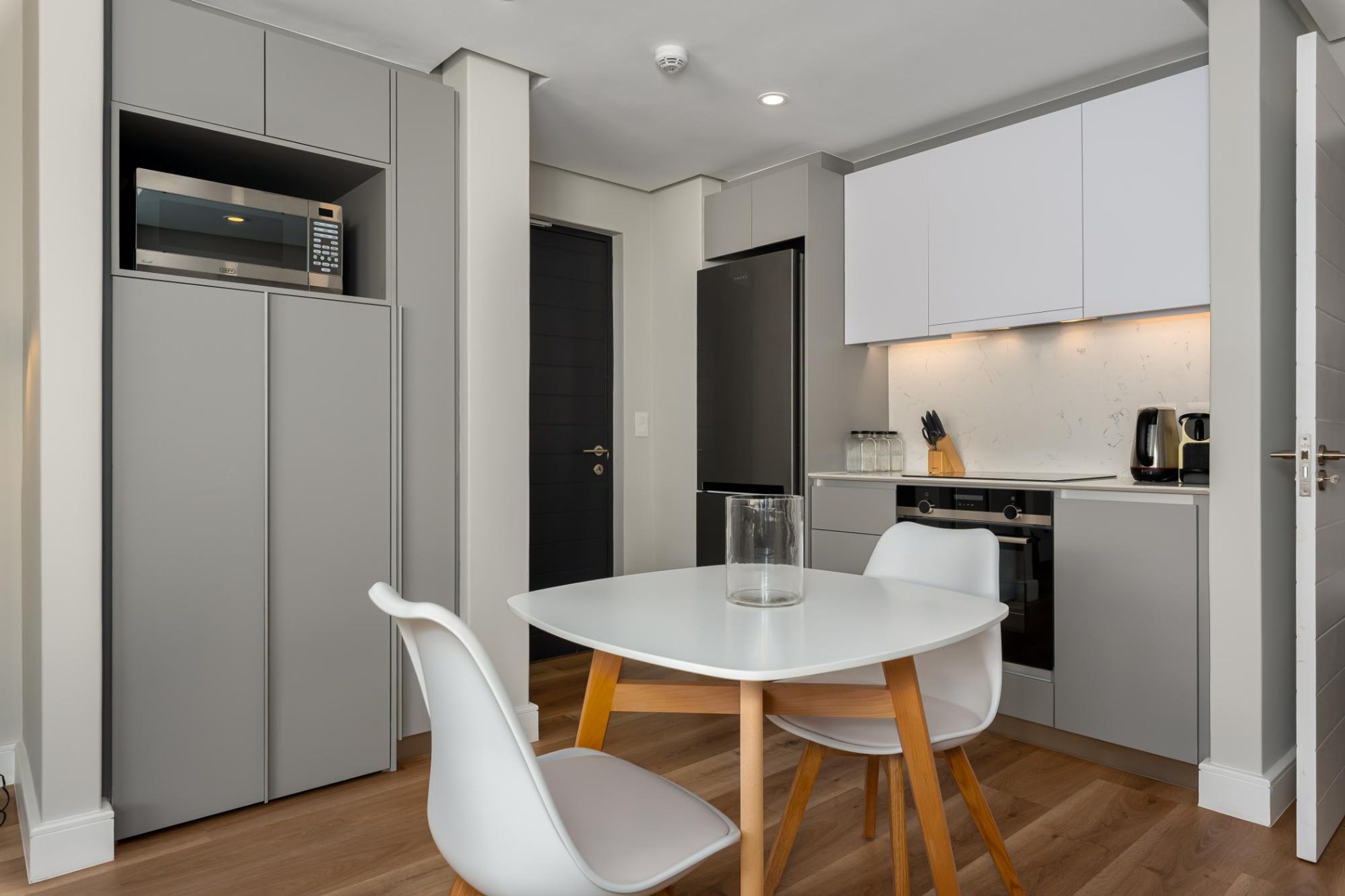 A compact kitchen with a microwave, refrigerator, and a small dining area with a table and chairs.
