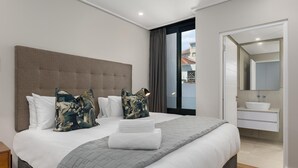 A modern hotel room with a large bed, grey bedding, and a view of the city through a large window. - Central Minimalist 1bed by the Ocean The Bantry (Cape Town)