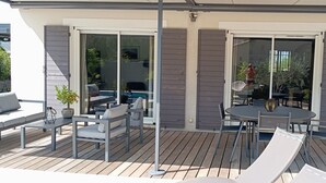 Une terrasse extérieure avec une table et des chaises, un canapé et une plante en pot.