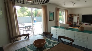 Une cuisine moderne avec des meubles blancs, une table à manger avec des chaises et une grande fenêtre avec des rideaux.