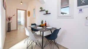 A dining area with a table set for four, surrounded by modern chairs, a decorative plant, and a fruit bowl.