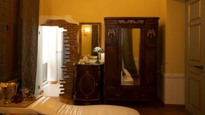 A room with a brick wall, a large mirror, a wooden cabinet, and a bed.
